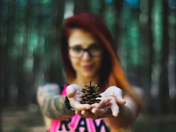 Portrait of woman holding pine cone in forest