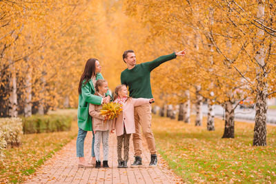 Full length of father with arms raised during autumn