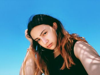 Portrait of a beautiful young woman against blue sky