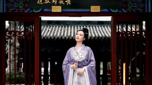 Portrait of young woman standing against trees