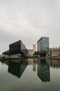 Reflection of buildings in lake against sky in city