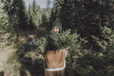 Woman with basket of spruce twigs in forest