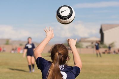 Rear view of woman playing with ball on field