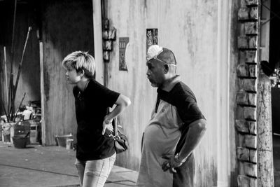 Side view of two people walking in front of street