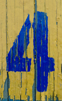 Close-up of damaged paint with number 4 on yellow wood