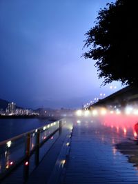 Illuminated bridge over river against sky at night