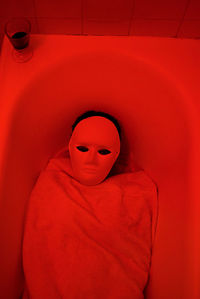 High angle view of woman wearing mask while lying in bathtub