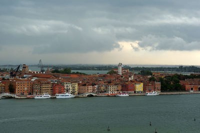 Sea by buildings against sky in city