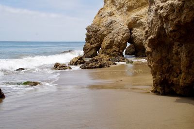 Rock formation on beach against sky