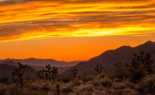 Scenic view of silhouette mountains against orange sky
