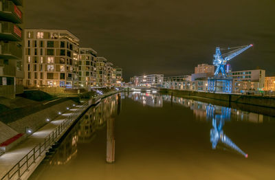 Reflection of buildings on river in illuminated city at night