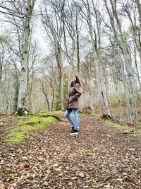 Full length of young woman standing at forest