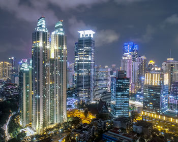 Illuminated buildings in city against sky at night