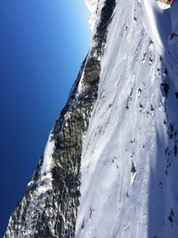 Low angle view of snowcapped mountain against clear blue sky