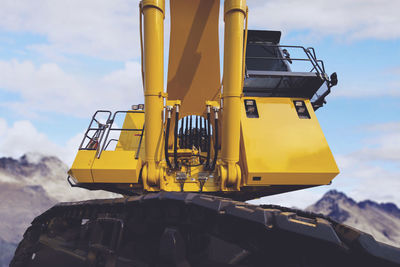 Low angle view of yellow construction machinery against sky