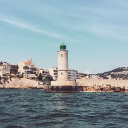 Lighthouse by sea against sky