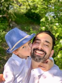 Portrait of cute son kissing father in park