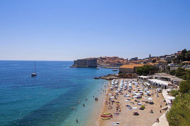 sea, water, beach, clear sky, copy space, horizon over water, shore, blue, built structure, sand, high angle view, architecture, building exterior, incidental people, coastline, scenics, vacations, tranquility, large group of people, nature