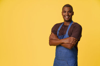 Portrait of young man standing against yellow background