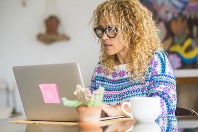 Smiling woman with coffee cup while working on laptop at home