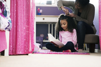 Woman combing daughter's hair at home