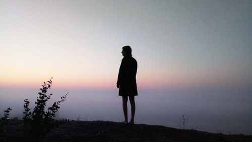 Silhouette man standing on cliff against clear sky