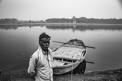 Man standing by boat on river against clear sky