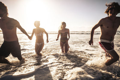 People enjoying at beach against sky