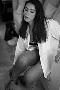 Young woman sitting on bed at home