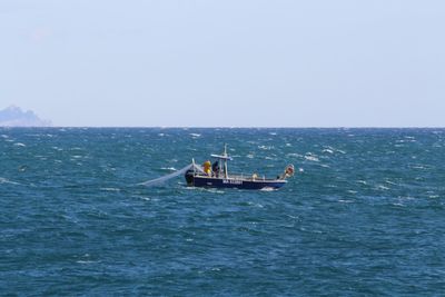 Boat sailing in sea against clear sky