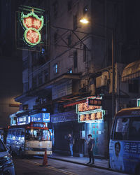 People walking on illuminated city street at night