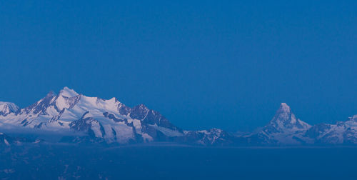 Scenic view of snowcapped mountains against blue sky