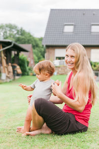 Portrait of woman with son sitting on field in yard