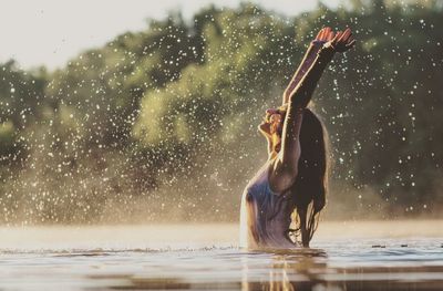 Woman enjoying in lake during sunset