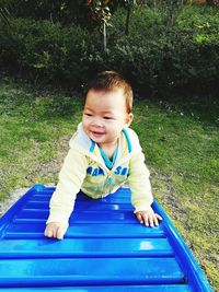 Portrait of smiling boy sitting on slide at park