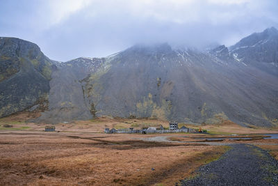 Distant view of ancient viking village under vestrahorn mountain against sky