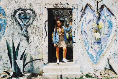 Portrait of smiling young woman standing against wall