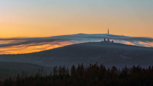 Silhouette of trees and buildings against sky during sunset