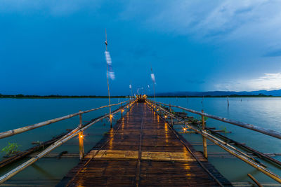 Wooden pier in lake against cloudy sky