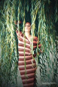 Portrait of young woman standing against plants