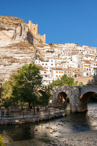 Arch bridge over river against buildings