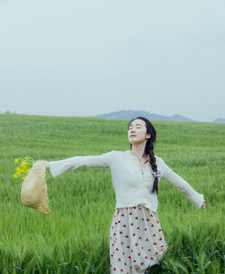 Portrait of woman standing on field against clear sky