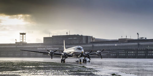 People at airport runway in city against sky