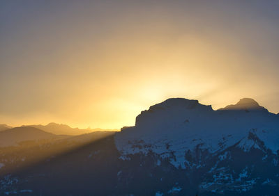 Scenic view of snowcapped mountains against sky during sunset