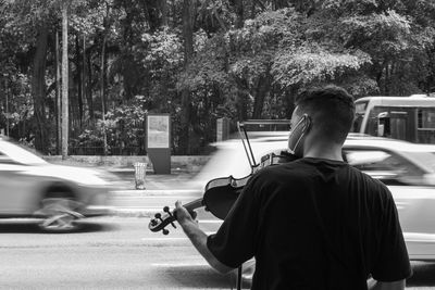 Rear view of man on street against trees in city