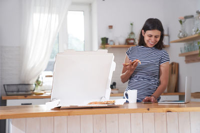 Portrait of young woman using laptop at home