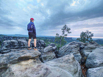 Alone tourist with baseball cap sporty clothes stand on edge. cloudy sky and early fall weather.