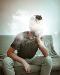 Young man looking away while sitting at home