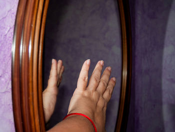 Close-up of man hand reflecting on mirror at home