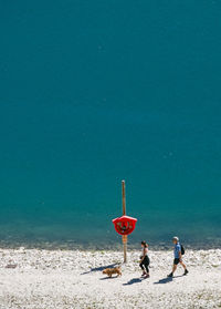 High angle view of woman with dog walking by man at lakeshore